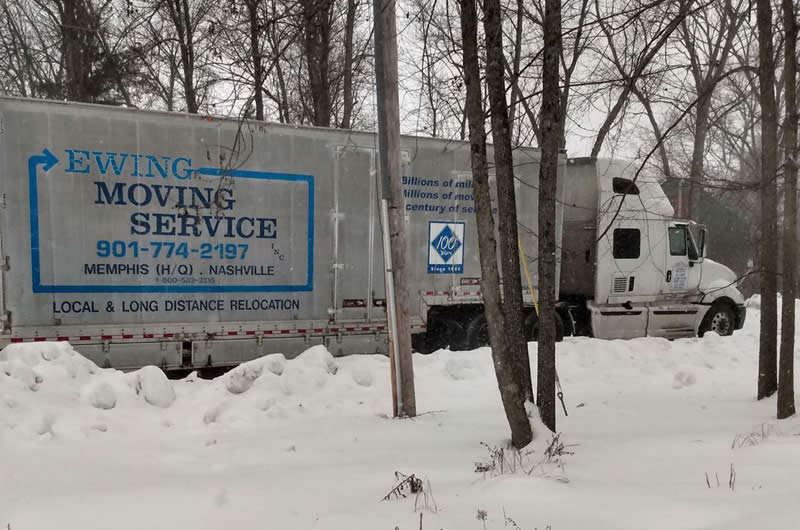 white moving truck on the road by the snow